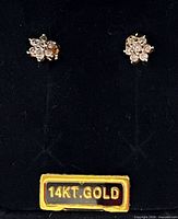 Front view of both diamond cluster earrings on display card marked 14KT GOLD