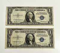 Front sides of both $1 silver certificates showing blue seals and serial numbers