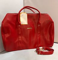 Front view showing bag, handles, tag, and shoulder strap