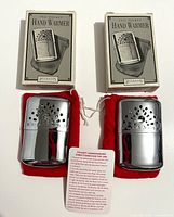 Full lot showing two boxed hand warmers with pouches and instruction card