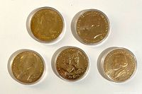 Obverse sides of five bronze commemorative medals in capsules