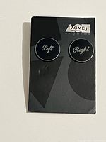 Front view showing both earrings on Acme Studios card