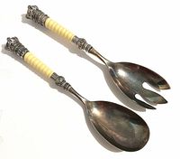 Both servers angled, showing metal heads and cream ribbed handles