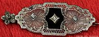 Front close-up of pendant brooch showing filigree, camphor glass, onyx and diamonds
