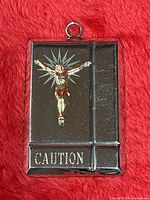 Front view showing gold Jesus figure, stainless steel plate, CAUTION engraving