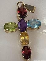 Front view of gold cross pendant showing gemstone arrangement and bail