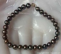 Full view of bracelet laid flat showing pearls and gold clasp