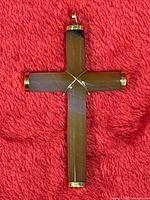 Full view of carnelian and gold cross pendant on red background