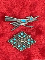 Overall view of both sterling silver turquoise pins on red background