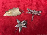 All three sterling silver brooches on red background