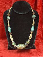 Full view of necklace on display bust showing bead arrangement and overall condition