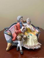 Front view of porcelain figurine showing couple seated on couch