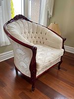 Front angle of carved wood barrel armchair with cream shell-pattern upholstery