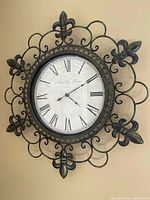 Front view of wall clock showing face, roman numerals, and decorative metal frame