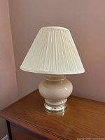 First beige glass table lamp with pleated shade on wooden surface