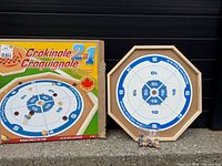 Front of box beside Crokinole face of board and discs