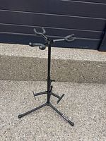 Full view of black metal multi-instrument stand upright on tripod base
