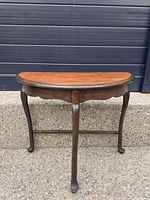 Front view of demi-lune table showing legs, stretcher and scalloped apron