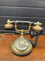 Front angle of brass-tone rotary-style desk telephone showing full item