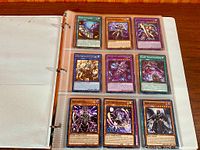 Binder open showing first page with nine Yu-Gi-Oh! cards in sleeves