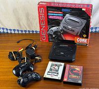 Entire bundle including console, retail box, controllers, cables, power adapter, Mortal Kombat and Madden NFL ’94 games displayed on table