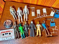 Group shot of eight figures, cassette, coin and accessories on wooden surface