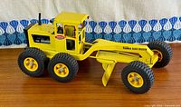Left side view of full grader showing decals and blade
