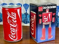Coca-Cola can robot beside its box front view