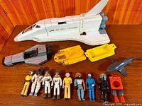 Group shot of shuttle, vehicles, shark and nine figures