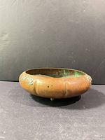 Side view showing ribbed copper body, floral appliqué and ball feet