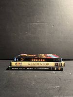 Three DVD cases stacked: Iron Man, Gladiator, Batman Begins spines visible