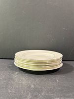Stacked view of seven matching 6.5" plates showing rim trim