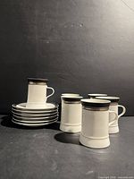 Group shot showing five upright cups, one cup on stack of six saucers