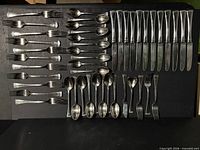 Overview of entire 49-piece stainless flatware lot laid out