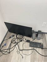 Monitor, speakers, surge protector and cables laid out on floor