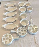 Full set laid out: five oval gratins, six ramekins, three escargot pans