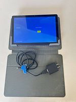Front view of powered-on onn. tablet in gray folio case with charger cable visible