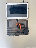 Tablet open in folio case with connected micro-USB cable and charger visible