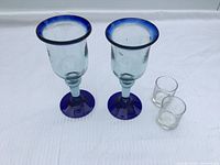 Front view of two blue-rim goblets and two shot glasses