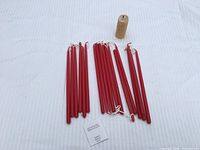 Group of 18 red taper candles and 1 rolled beeswax pillar on white background