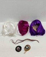 Three wigs and three hairpieces laid out