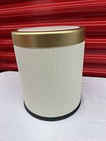 Closed wastebasket showing cream ribbed body and gold-tone lid