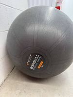 Full view of inflated grey Mantra Sports exercise ball leaning against wall