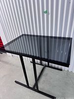 Full view of table from top angle showing smoked glass top and metal frame