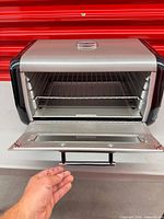 Oven door open showing interior rack and crumb tray