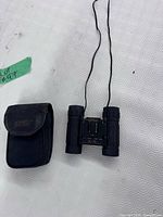 Binoculars folded open beside Optex pouch