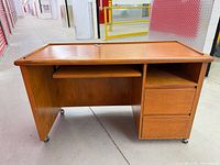 Angled front view showing full desk, keyboard tray, drawers and casters