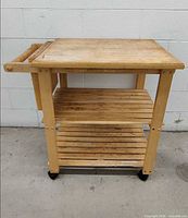 Full view of wooden cart showing top, two slatted shelves, towel bar and casters