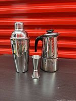 Cocktail shaker, jigger, and moka pot side by side