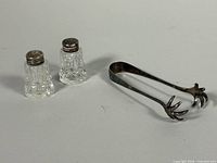 Full view of both crystal shakers and silver tongs